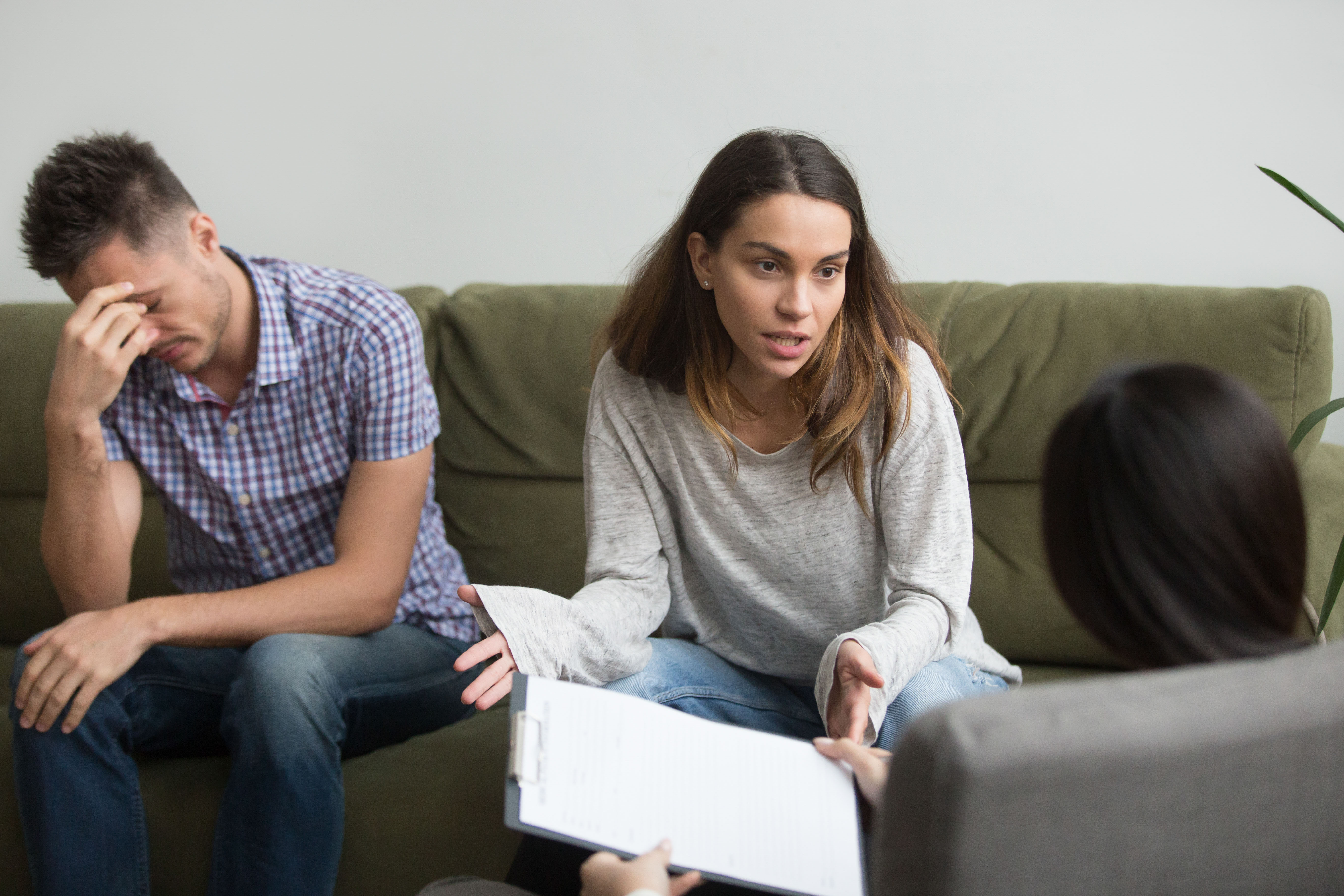 Frustrated stressed wife talks to psychologist about bad relationships sitting on couch with husband, unhappy woman sharing problems with counselor, couple counseling, family marriage therapy session